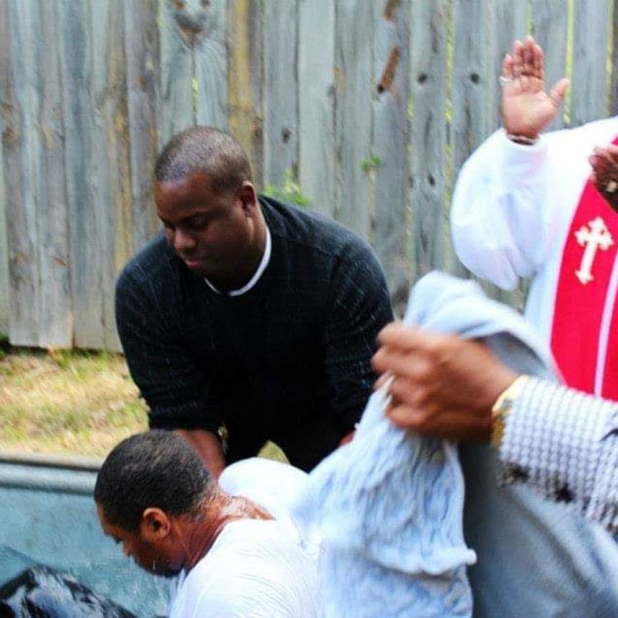 A member of Christ Family Church being baptized by Pastor Dennis Hood, who wears a white and red clergy stole.